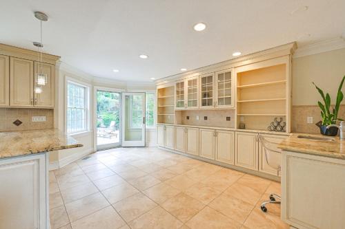 a large kitchen with wooden cabinets and tile floors at Private Pool and Patio Luxe Westchester Home! in Briarcliff Manor