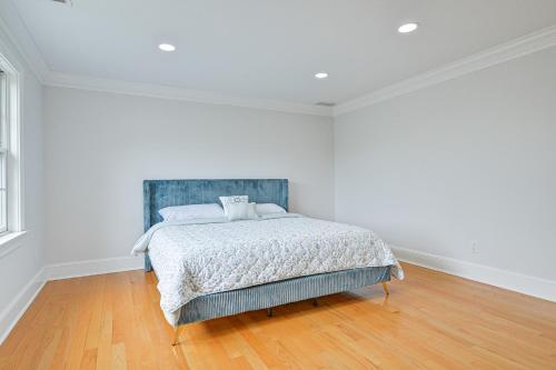 a bed in a white room with a wooden floor at Private Pool and Patio Luxe Westchester Home! in Briarcliff Manor