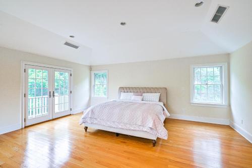 an empty bedroom with a bed and two windows at Private Pool and Patio Luxe Westchester Home! in Briarcliff Manor