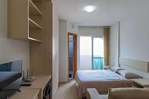 Un dormitorio con una cama, un escritorio y un televisor. en Prédio Central, en Curitiba