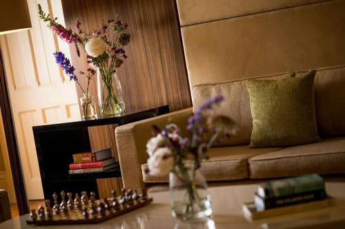 a living room with a couch and a vase of flowers at St Pancras London, Autograph Collection in London