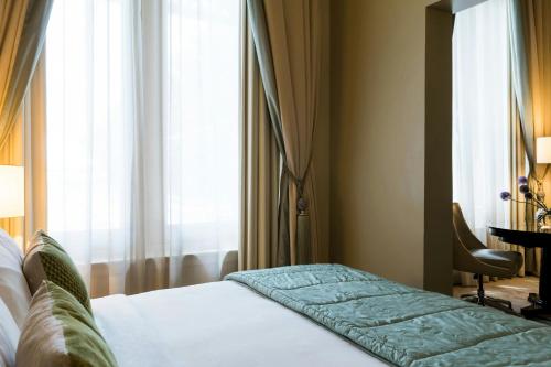 a bed in a hotel room with a window at St Pancras London, Autograph Collection in London