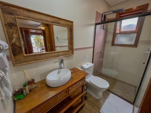 a bathroom with a sink and a toilet and a mirror at Casa Melville Hospedagem - Sua Casa de Alto Padrão no Coração de Ubatuba! in Ubatuba