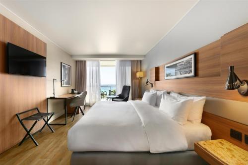 a hotel room with a large white bed and a desk at Radisson Blu Hotel Nice in Nice