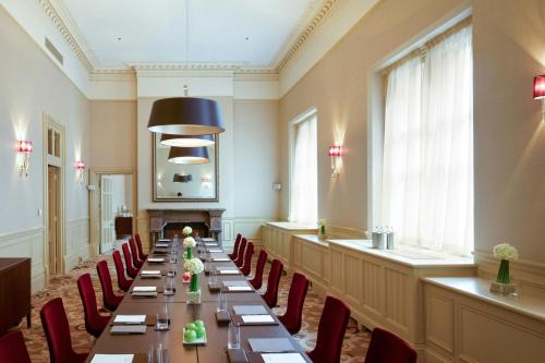 a long dining room with a long table and red chairs at St Pancras London, Autograph Collection in London