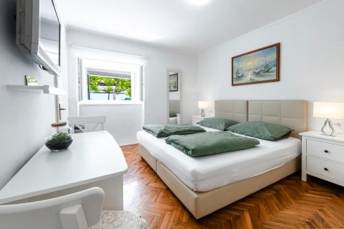 a white bedroom with a bed and a desk at Radovčić Apartments and Rooms in Trsteno