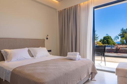 a bedroom with a bed and a large window at Alkida Luxury Rooms Tolo in Tolo