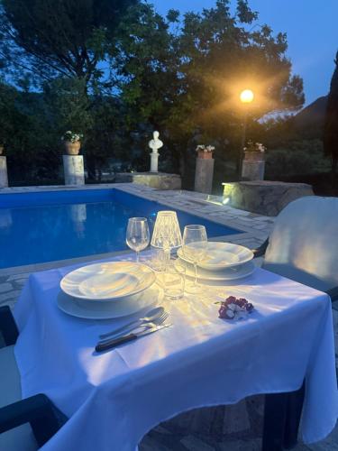 a table with plates and wine glasses next to a pool at Casa Bianca in Vaiano
