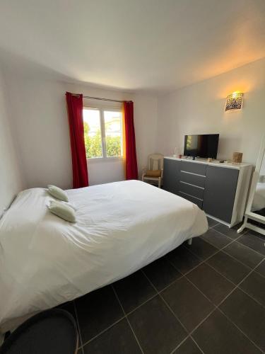 une chambre avec un grand lit blanc et une télévision dans l'établissement Villa Moderne avec Piscine - proche Montpellier, à Jacou