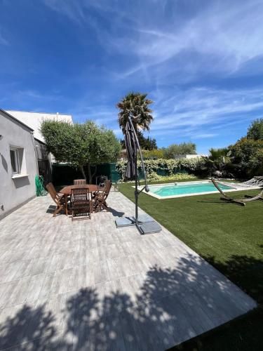 - une terrasse avec une table et un parasol à côté de la piscine dans l'établissement Villa Moderne avec Piscine - proche Montpellier, à Jacou