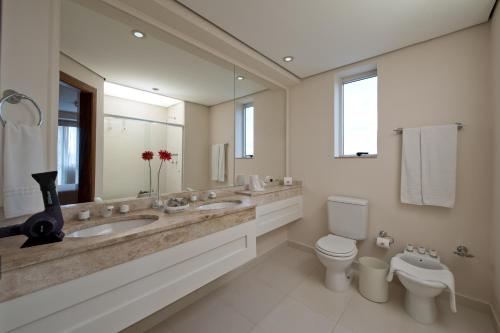 a bathroom with two sinks and a toilet and a mirror at Hotel Sequoia Alphaville in Barueri