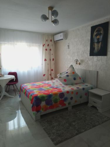 a bedroom with a bed and a table and a window at Apartament IRI Băile Herculane in Băile Herculane