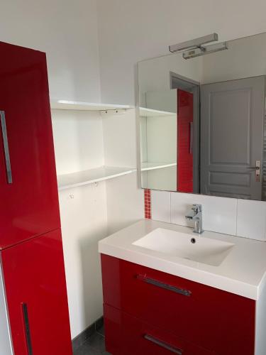 La salle de bains est pourvue d'un lavabo et d'une armoire rouge. dans l'établissement Villa Alfabeta, à Bizanet