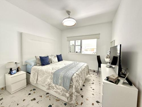 a white bedroom with a bed and a television at Villa Stay & Enjoy in Antigua