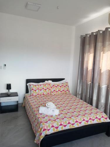 a bedroom with a large bed with a yellow and pink bedspread at Ibis Tourist Residence 1 in Mahébourg