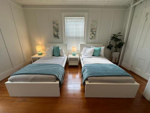 two beds in a room with two lamps on tables at Charming Victorian Home Downtown Newport in Newport