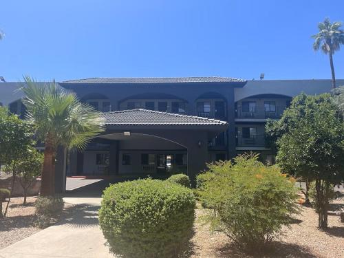 a large blue building with a palm tree and bushes at Ocotillo Apartments & Hotel in Phoenix