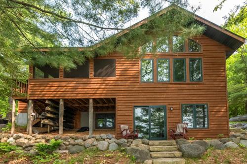 a log cabin with two chairs in front of it at The Cedar Lakehouse in Lake Tomahawk WI in Lake Tomahawk