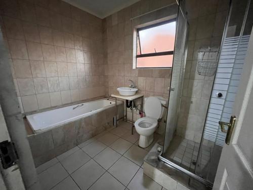 a bathroom with a tub and a toilet and a sink at Tanya's home in Johannesburg