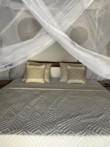 a bed with curtains and pillows in a bedroom at Adjana in Ngaring