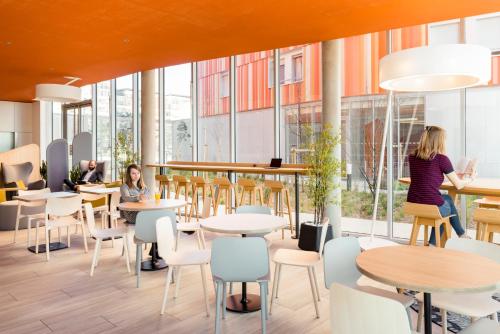 a group of people sitting at tables in a cafeteria at Aparthotel Adagio Access Paris Massy Gare in Massy