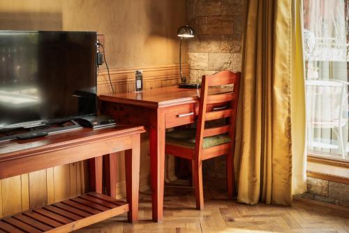 a wooden desk with a chair next to a desk with a television at Shivadya - A Luxury Boutique Experience in Manāli