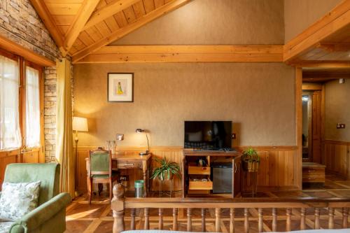 a living room with a television and a table with a couch at Shivadya - A Luxury Boutique Experience in Manāli
