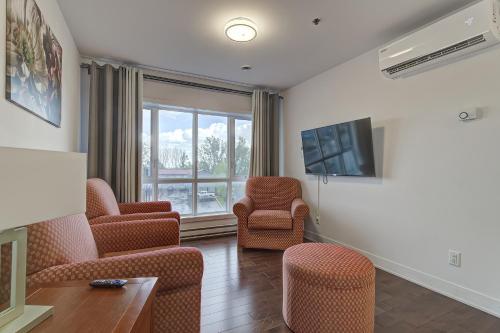 a living room with chairs and a flat screen tv at Le Bijou Airhome in Montréal