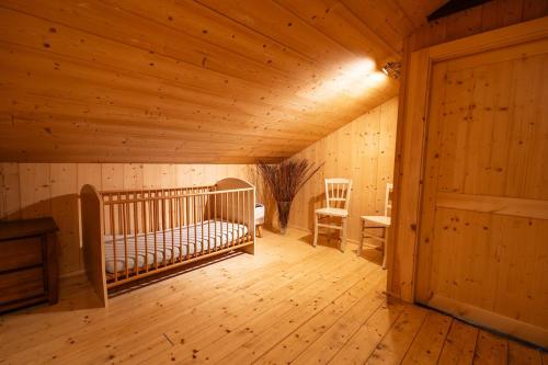 Zimmer mit Kinderbett in einem Holzzimmer in der Unterkunft Aux Sources - 14 personnes - sauna & jacuzzi in La Bresse
