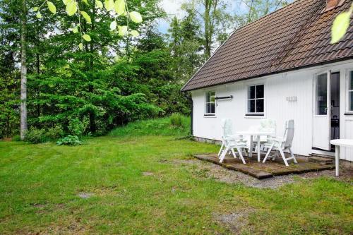 a white house with a table and chairs in the yard at Peaceful cabin with fireplace in the middle of nature in Höör