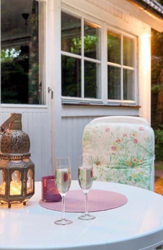 two glasses of wine on a table with a chair at Peaceful cabin with fireplace in the middle of nature in Höör