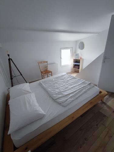 un grand lit blanc dans une chambre avec une fenêtre dans l'établissement Maison familiale proche Thermes, Lac et Plages, à Saujon