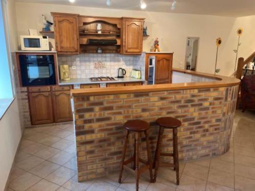 - une cuisine avec un bar en briques et 2 tabourets dans l'établissement gite de saintre, à Juilley