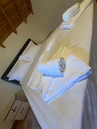 a bed with white sheets and towels on it at Bedena House in Kolonjë