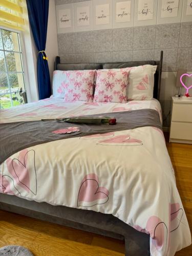a bedroom with a bed with pink hearts on it at FINN VILLAGE "Raspberry Cottage" Private Garden, 6-seater HOT TUB, Firepit & Pizza Stove in Drymen