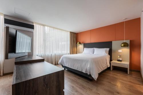 a bedroom with a bed and a flat screen tv at Hotel Holiday Inn Express & Suites Medellin by IHG in Medellín