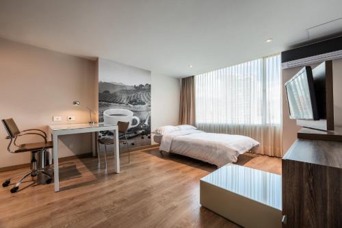 a bedroom with a bed and a desk and a television at Hotel Holiday Inn Express & Suites Medellin by IHG in Medellín