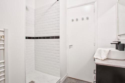 une salle de bain blanche avec une douche et un lavabo dans l'établissement Maison NASTIA, à Caen