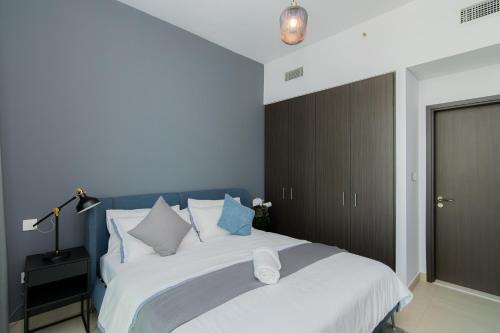 a bedroom with a large white bed with blue walls at Elite Escape Holiday Home - 1 BHK Getaway with Dubai Mall Access - 3310 in Dubai