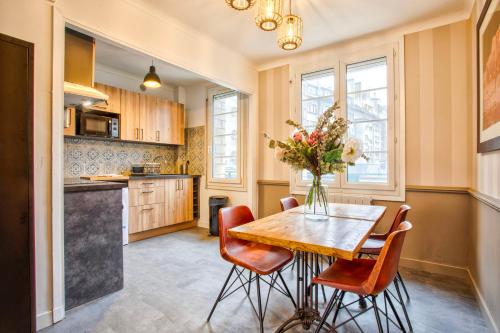 une cuisine avec une table en bois et des chaises rouges dans l'établissement Maison NASTIA, à Caen
