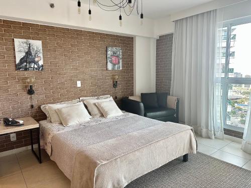 a bedroom with a large bed and a brick wall at Ed Saint Moritz, Flat 02 com Garagem, SHN no Coração de Brasília in Brasilia