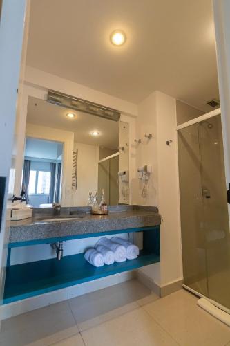 a bathroom with a sink and a large mirror at Prime Flat - Metrópolis Alphaville in Barueri