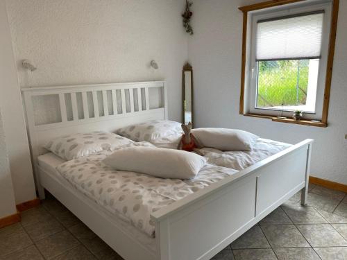 a white bed with pillows on it in a bedroom at Ferienwohnung zur Töpferstube 2 - 2025 in Spabrücken