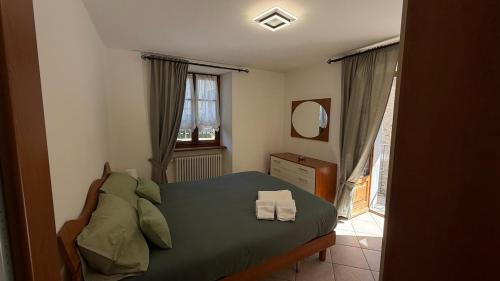 a bedroom with a bed with green sheets and a mirror at Da Mamaa casa vacanze in Toceno