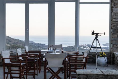 a camera on a tripod in a room with a table and chairs at Perla Pool Hotel Andros in Ménites