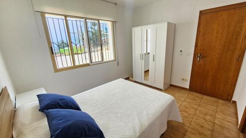 a bedroom with a bed with blue pillows and a window at Céntrico La Cova para 8 Pax con Plaza de Garaje in Peñíscola