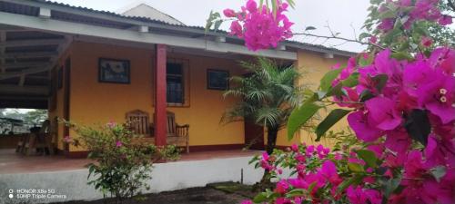 una casa amarilla con flores rosas delante en Hacienda Quele'ya, en Yepocapa