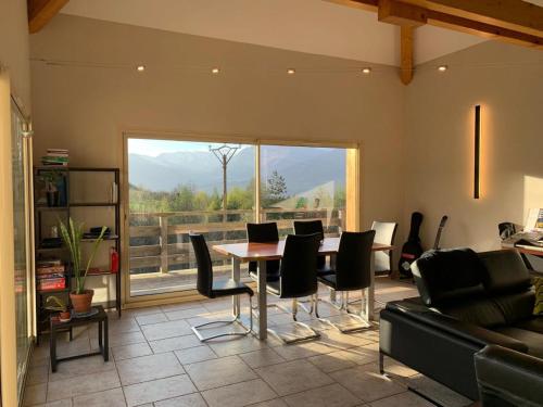 - un salon avec une table, des chaises et une grande fenêtre dans l'établissement Grande maison, calme et montagnes, à Crots