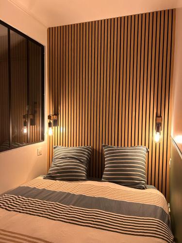 a bed with two striped pillows in a bedroom at Un cocon tout confort à La Rochelle - proche gare & plages in La Rochelle