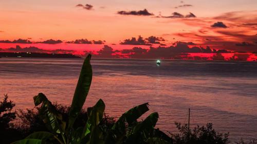 a sunset over the ocean with a boat in the water at Oasis d'Happy Bay with SPA, Frontbeach, Amazing sunset on Anguilla in Friar's Bay